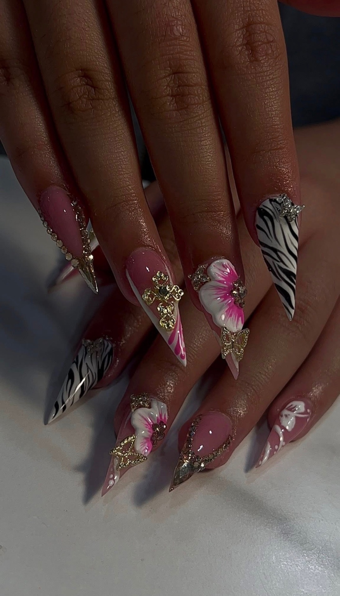 Pink stiletto nails with zebra, gold cross, 3D hibiscus & butterflies