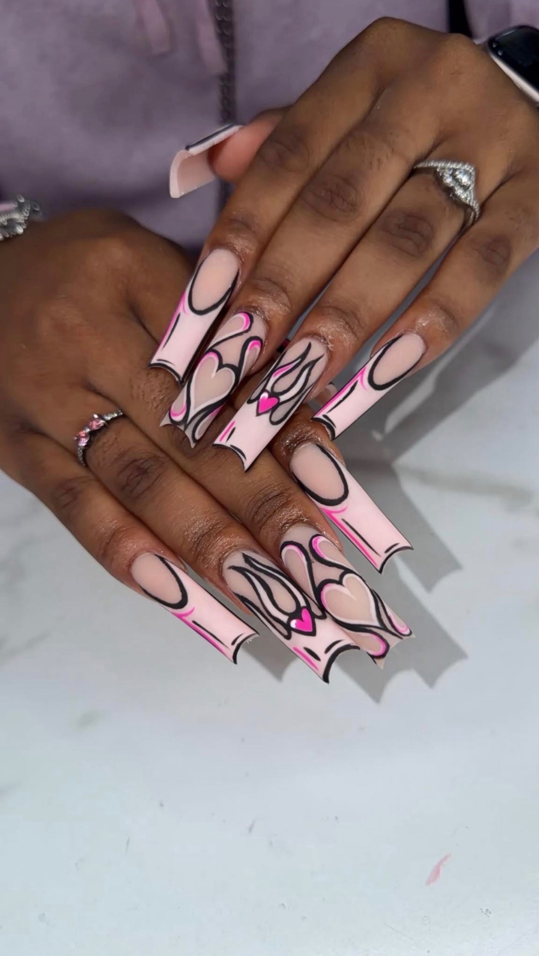 Pink French tips with hand-painted black swirls and hearts